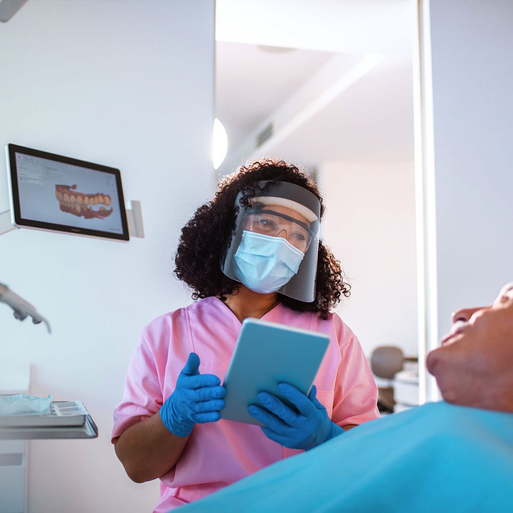 Dentist speaking to patient wearing full PPE